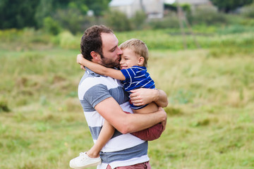 Fototapeta premium Father holds his son at the hands face-to-face on a nature. Son hugging his father.