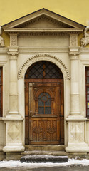 Antique classic pastel marble facade with rough rustic sculptured wooden door and old monochrome stained glass. Vertical toned image.