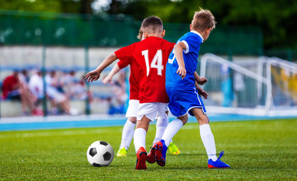 Boys Kicking Soccer Ball on Grass Pitch. Children Football Players Playing Match on the Stadium. Soccer Game for Kids