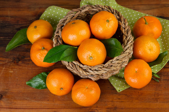 basket of tangerines with green napkin on dark wood top view