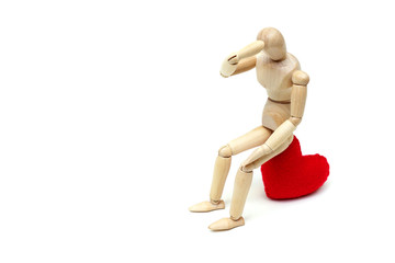 Wood Figure Mannequin sitting sadly on a red heart waiting for love