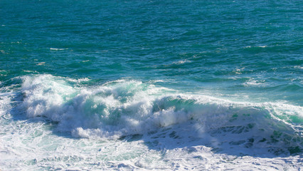 Obraz premium Beautiful sea waves splash with white foam on a blue ocean surface background.