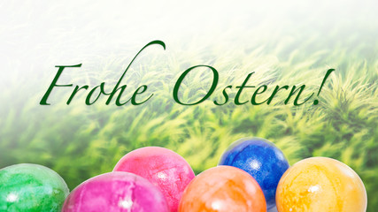 Frohe Ostern! Bunte Ostereier und Ostergras mit Schriftzug