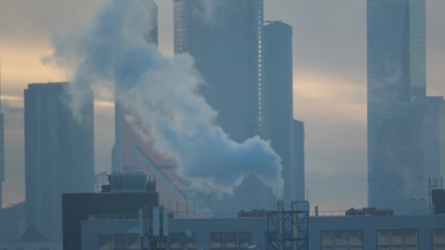 Air pollution from industrial plants. Large plant on the background of the Moscow City. Pipes throwing smoke in the sky. Cold russian winter. Smoke from an industrial thermal chimney,  power plant.