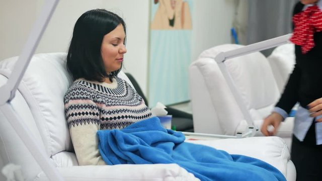 Young girl sits in a folding chair at the beauty salon and talking with the master