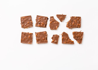 Broken milk chocolate pattern, top view flat lay on background