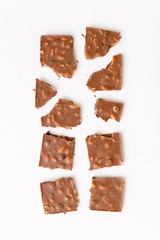 Broken milk chocolate pattern, top view flat lay on background