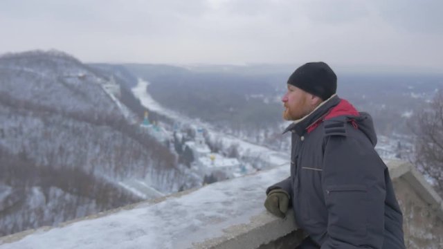 a Religious Bearded Man Looking at Sviatogorskaya Lavra, Situated in Picturesque Mountains, From the Observation Deck of Artyom Monument in Winter