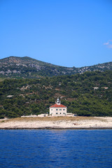 Fototapeta na wymiar Picturesque lighthouse on a small island in the Adriatic Sea. Near town Hvar, island Hvar, Croatia. 