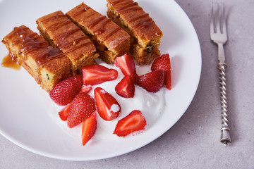 White ceramic china plate silver steel fork slices of carrot cake dessert sweet watered caramel and fresh strawberries and cream delicious healthy nutritious breakfast.