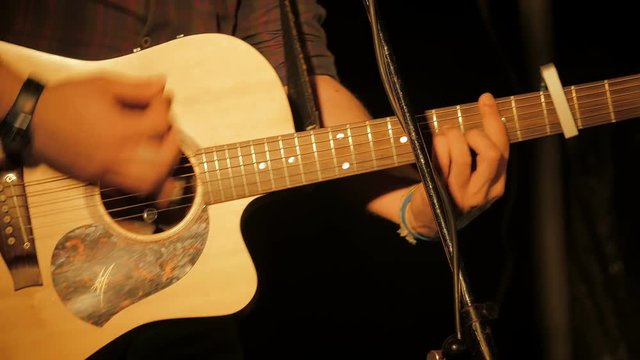 musician hands deftly plays acustic guitar during a concert