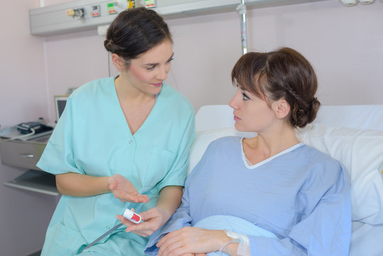 Nurse Giving Medication To Patient In Hospital