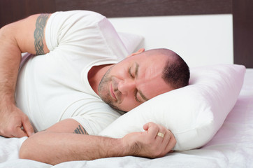 Fototapeta na wymiar Muscular handsome young man with arm tattoos sleeping peacefully