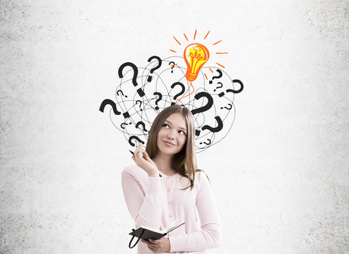 Girl with notebook, light bulb and question marks