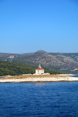 Fototapeta na wymiar Picturesque lighthouse on a small island in the Adriatic Sea. Near town Hvar, island Hvar, Croatia. 