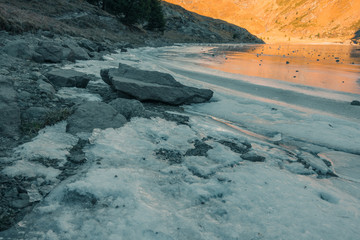 Fototapeta premium Iced lake between the mountains at sunset