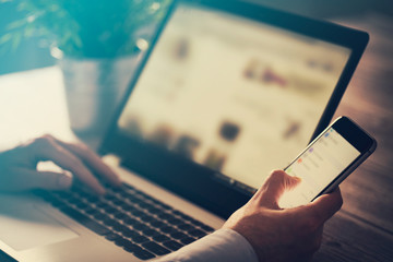 Man using laptop and phone.