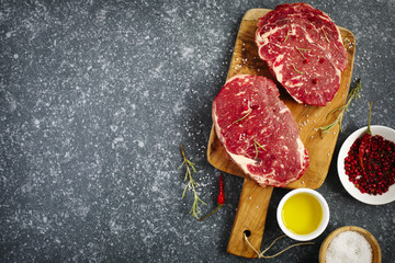 Raw fresh meat Ribeye Steak with rosemary, pepper, salt and olive oil