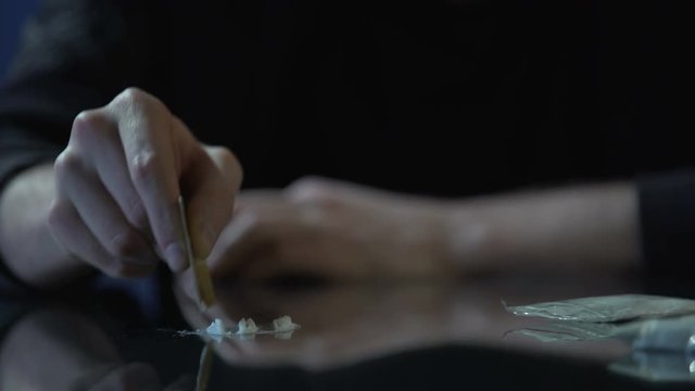 Close-up of male hand making lines of cocaine dose, drug addiction problem