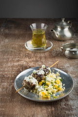 Moroccan meatballs served over couscous on a vintage pewter plate. Mint tea in the background. 