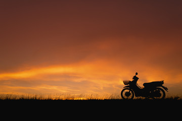 Orange sunset sky. Silhouette motorcycle in sunset landscape bac