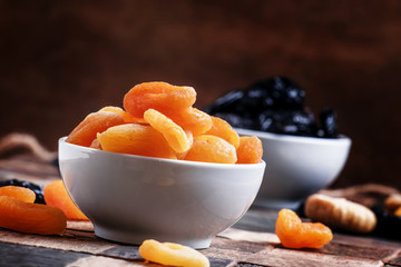 Dried apricots in bowl, vintage wooden background, selective foc