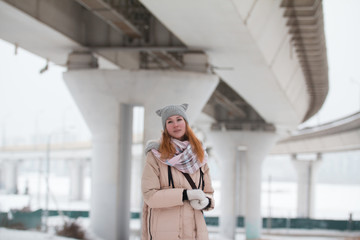 Obraz premium Portrait of young woman stands under large bridge, modern winter city