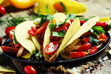 Mexican tacos stuffed with meat, beans, tomatoes and chili peppe