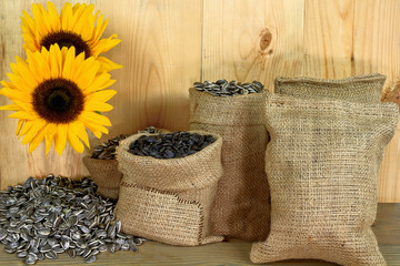 Sunflower seeds, burlap bags, sunflower blossom, wooden table an