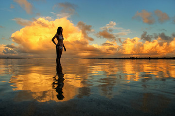 Silhouetted woman standing in a water at sunset on Taveuni Islan