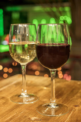 Red and white wine glasses on blurred lights background