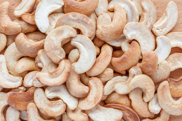 Close up pile of cashew nuts on wooden board background.
