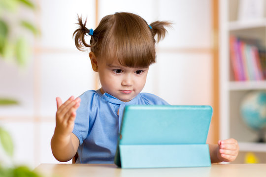 Surprised little girl looking at her tablet pc