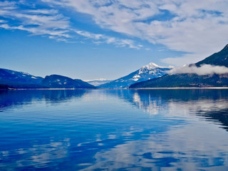 Fototapeta na wymiar Blue lake and blue snowy mountains. Upper Arrow lake. Columbia River. Selkirk and Monashee Mountains. Keenleyside Dam. Castlegar. Revelstoke. British Columbia. Canada.