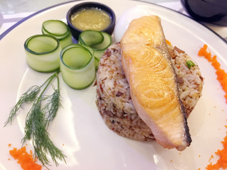 Fried salmon on the rice served with preserved cucumber and sour