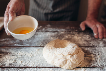 Making dough for bread or pie free space. Baker standing at kitchen table with eggs and raw pastry. Bakery, cooking, hobby concept