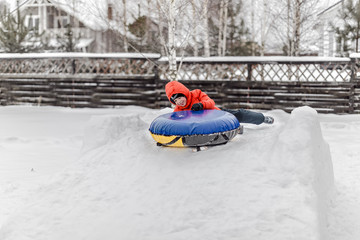 Fototapeta na wymiar Boy with the inflatable sledge, snow tube, inner tube, lies on snow