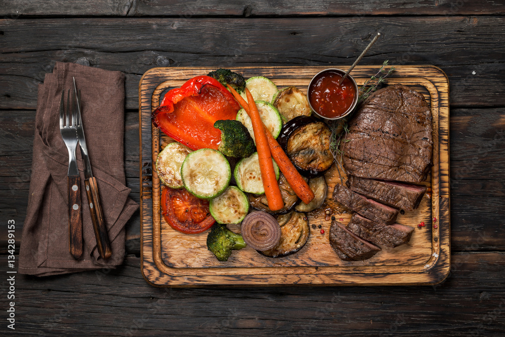 Poster Sliced steak with grilled vegetables on the wooden table