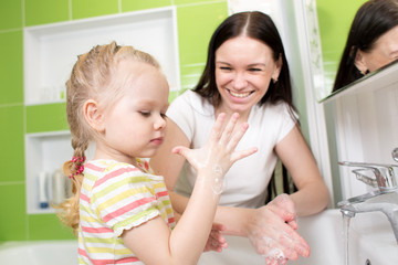 child girl washing hands with soap in bathroom