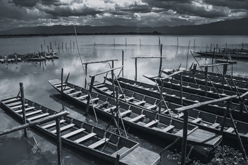 Obraz premium empty wooden fishing boat parking at lake shore in quiet lake sky black and white tone.
