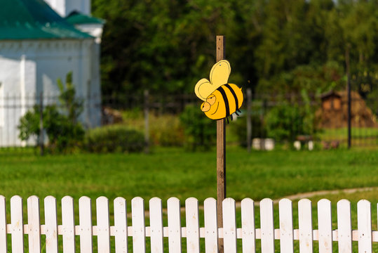 The plate in the form of a bee over a white fence.