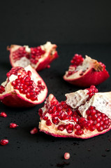 Whole and sliced pomegranate on a black background