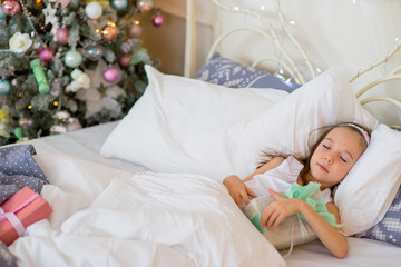 Fototapeta na wymiar Child girl sleep in her bed in Christmas morning