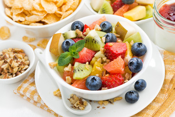 breakfast with fruit salad and corn flakes on white table