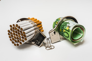 Cigarettes and money with handcuffs - cost of smoking