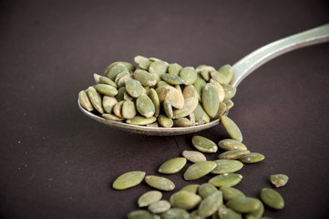 Pumpkin seeds in a spoon on a dark background