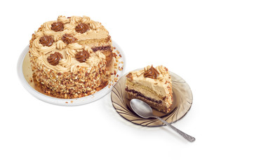 Piece of layered sponge cake on saucer, partly sliced cake