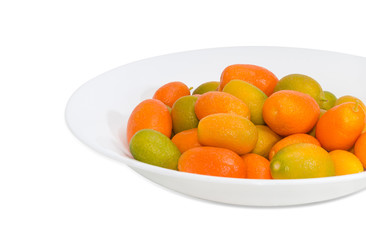 Kumquats on white dish closeup on a light background