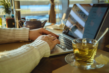male sitiing in caffe drinking tea and working on laptop