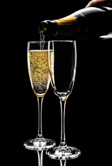 mans hand pours champagne from bottle into glass, close up